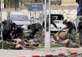 Policías israelíes examinan los cadáveres de combatientes palestinos frente a una comisaría en la ciudad de Sderot.