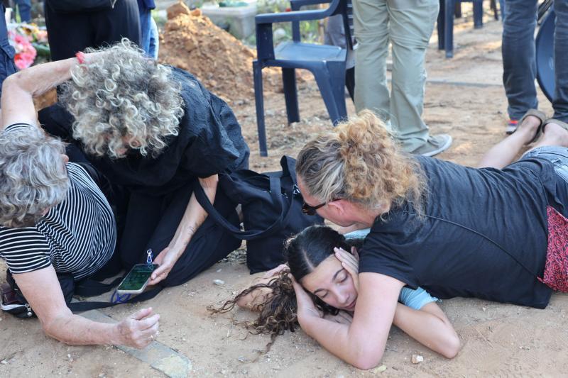 Familiares de un soldado fallecido se arrojan al suelo mientras suenan las sirenas antiaéreas durante el funeral en Tel Aviv.