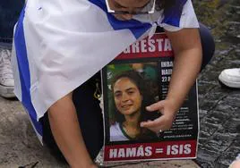 Una joven coloca velas en el suelo mientras porta el retrato de una mujer desaparecida.