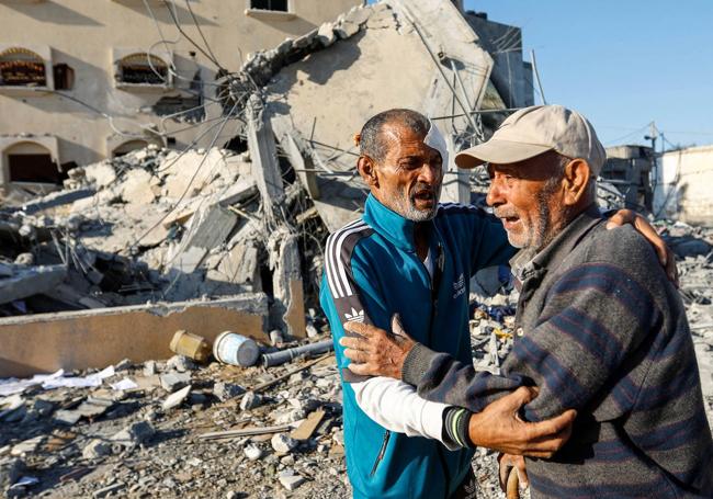 Dos hombres se abrazan entre los escombros en Gaza.