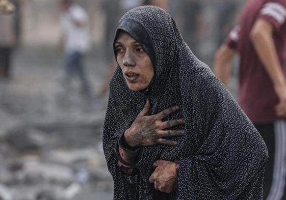 Una palestina sale cubierta de polvo tras el bombardeo de su vivienda.