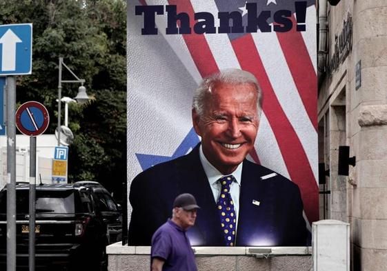 Un hombre pasa frente a un cartel gigante del presidente de EE UU, Joe Biden, en una calle de Jerusalén