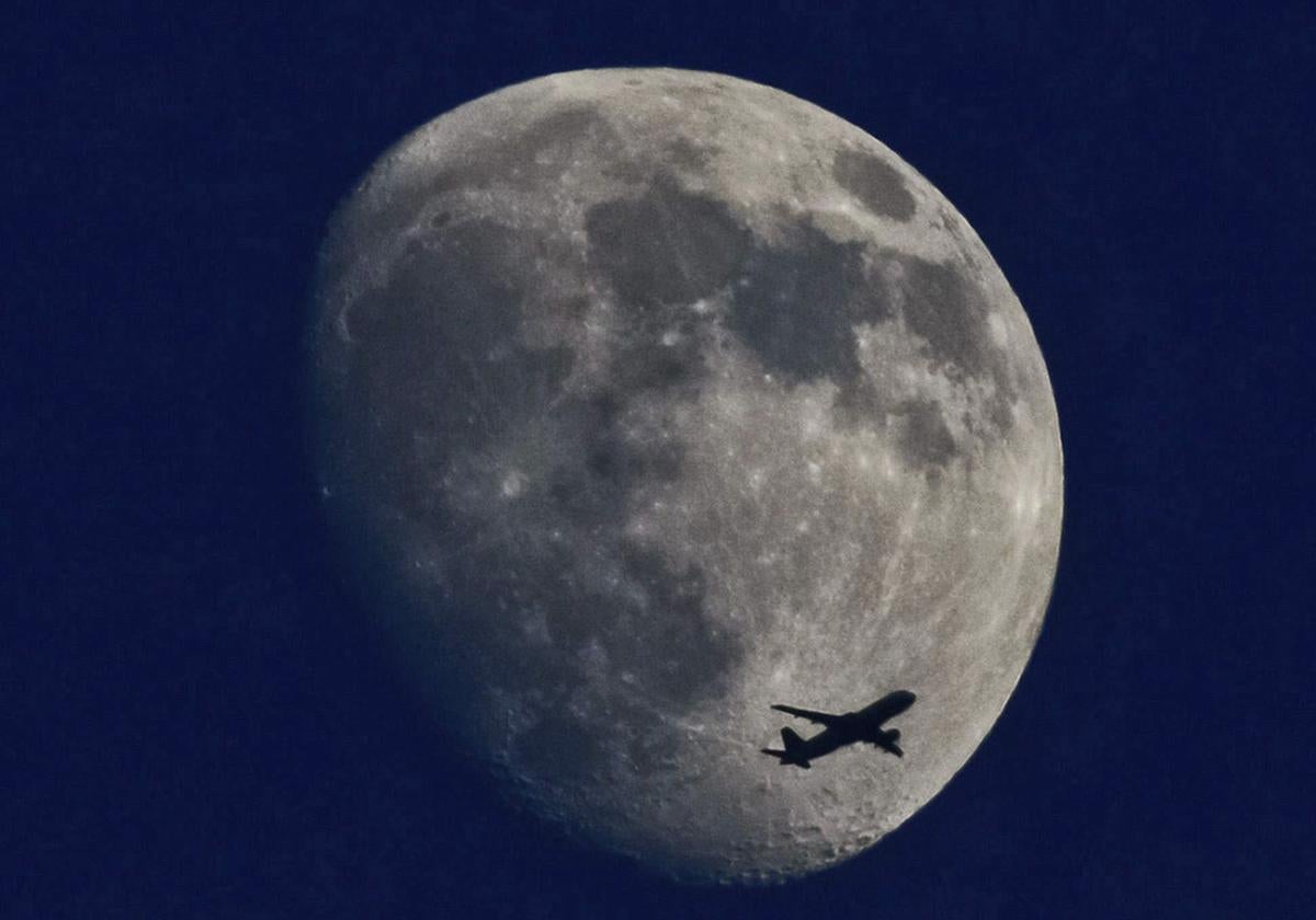 Un avión vuela con la luna creciente de fondo en Fráncfort, Alemania.