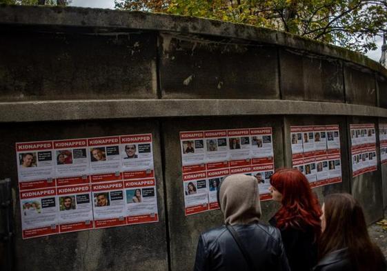 Un grupo de jóvenes observa en un muro fotografías de las personas retenidas ppr Hamás.