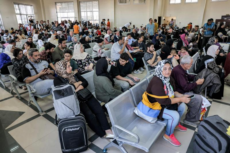 Gente esperando en el cruce fronterizo de Rafah, en el sur de la Franja de Gaza, antes de cruzar a Egipto