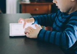 Un niño mira una tablet.