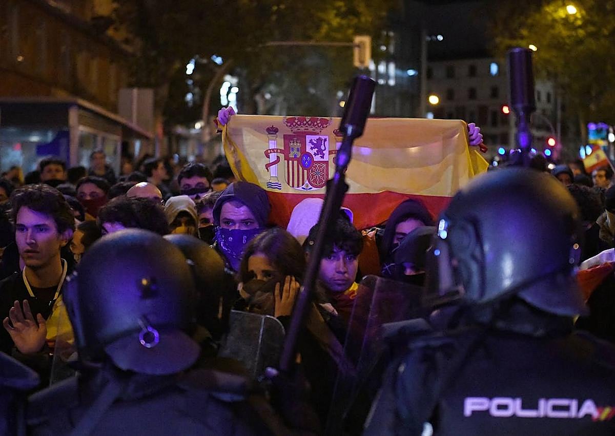 Imagen secundaria 1 - En la imagen superior, un policía intenta detener a un manifestante; debajo, un grupo de manifestantes con la bandera de España, algunos encapuchados, frente a varios agentes antidistubios; por último, un policía dispuesto a lanzar pelotas de goma tras producirse los primeros altercados violentos. 