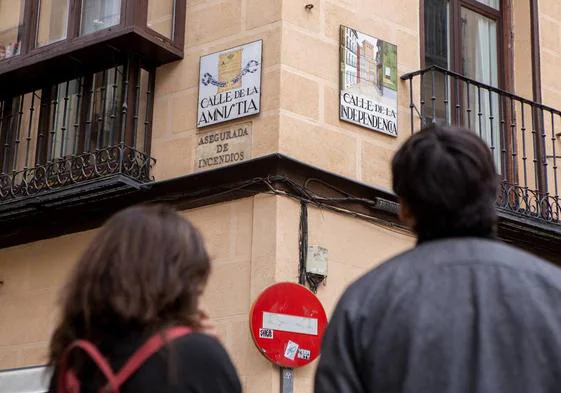 Una pareja observa los letreros de las calles de la Amnistía y de la Independencia, en el Madrid de los Austrias, a unos pasos del Teatro Real.
