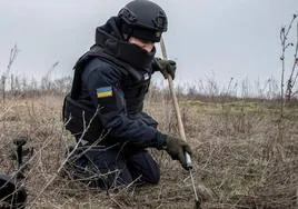 Un miembro del Servicio Estatal de Emergencias inspeccionan una zona en busca de minas y proyectiles sin detonar en Járkov, en Ucrania