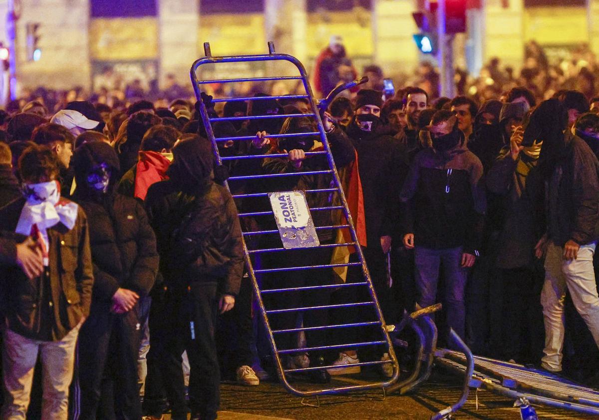 Imagen principal - En la imagen superior, radicales y encapuchados se hicieron una noche más con la cabecera de la concentración de protesta a última hora; debajo, dos policias antidisturbios agarran a una persona envuelta con la bandera española y, por último, uno de los contenedores que fueron quemados por los violentos cerca de la madrileña calle Ferraz durante los altercados.