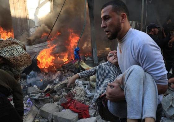 Un hombre evacua a una niña herida tras un bombardeo israelí.