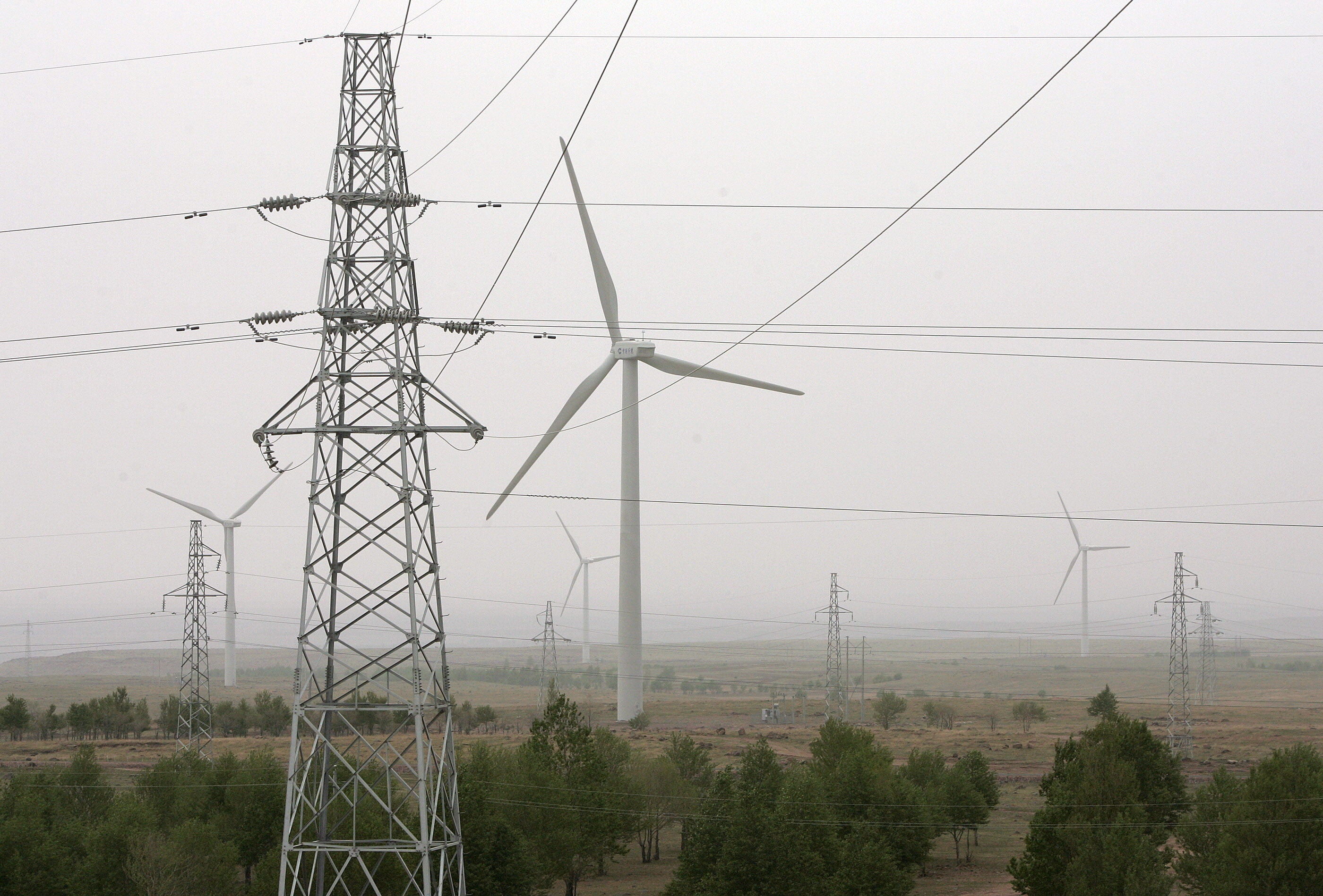 Vista de lineas electricas enfrente de un aerogenerador.