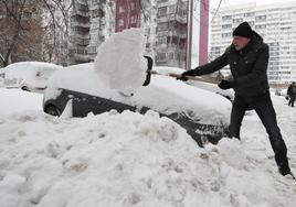 Un hombre retira nieve de un vehículo con una pala en el centro de Moscú.