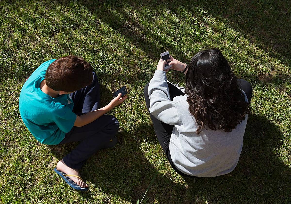 Dos jóvenes, mirando el móvil.