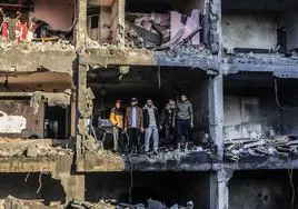 Varios palestinos examinan los restos de un edificio bombardeado ayer por Israel en Rafah.