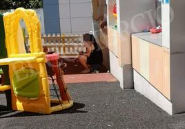 Fotografía incluida en la denuncia, en la que se puede ver a un niño en el alféizar de una ventana del patio y a la profesora con el móvil.