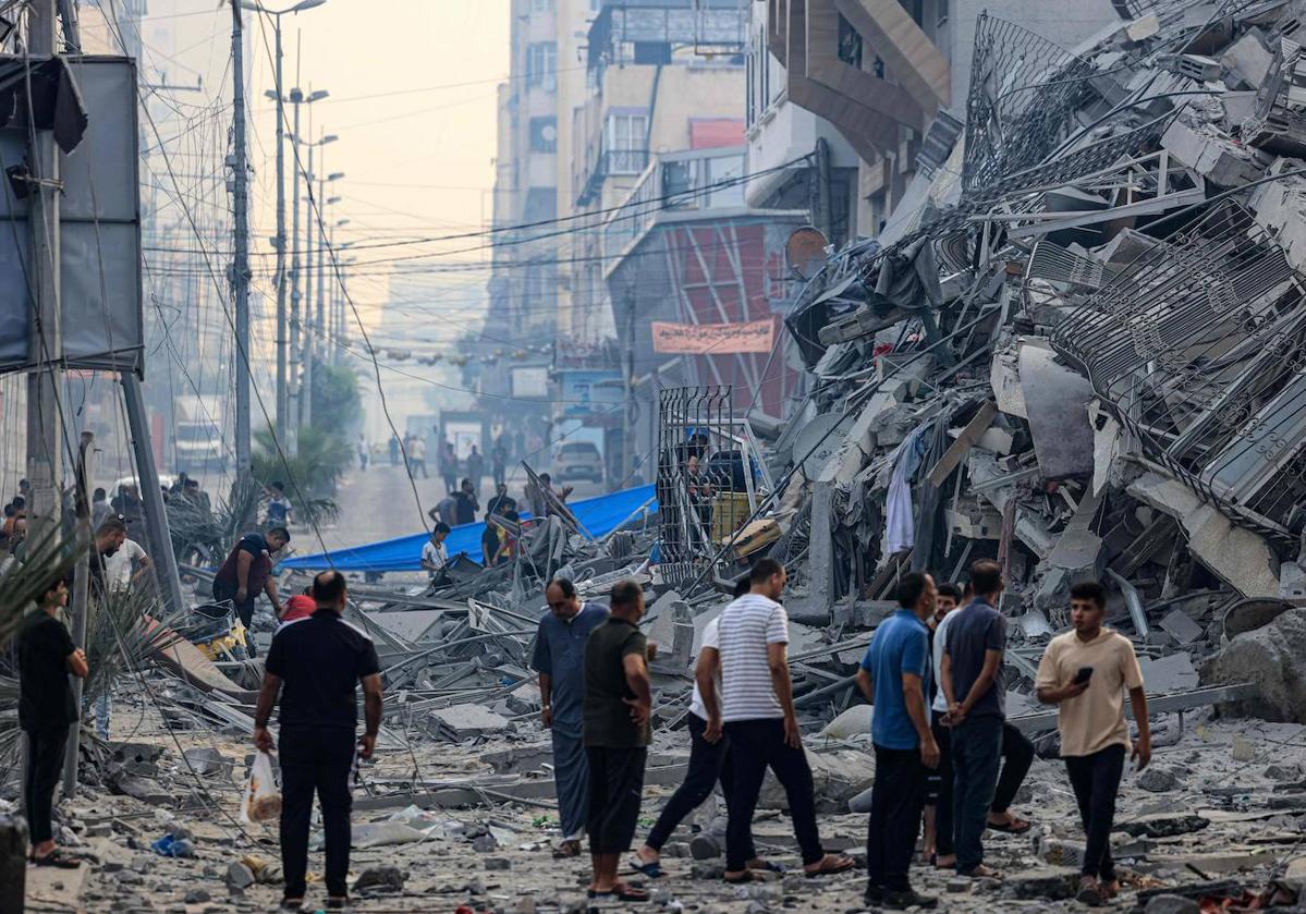 Un grupo de gazatíes observan los escombros de un edificio destruido por la aviación israelí.