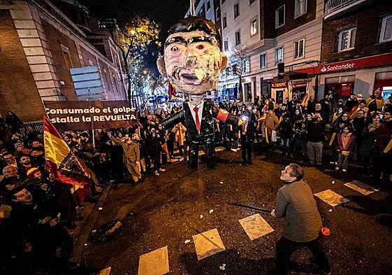 Uno de los asistentes a la concentración convocada en Nochevieja por una organización afín a Vox cerca de la sede socialista golpea a un muñeco caracterizado como Pedro Sánchez.