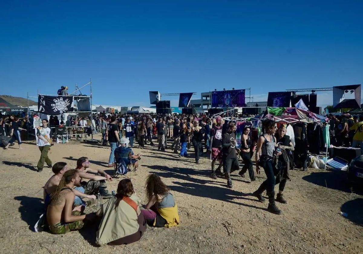 Imagen principal - En la imagen superior, aspecto de la zona del recinto donde han instalado diversos puestos; debajo, los asistentes a la 'rave' en pleno festejo musical y, por último, aspecto de la zona improvisada de aparcamiento.