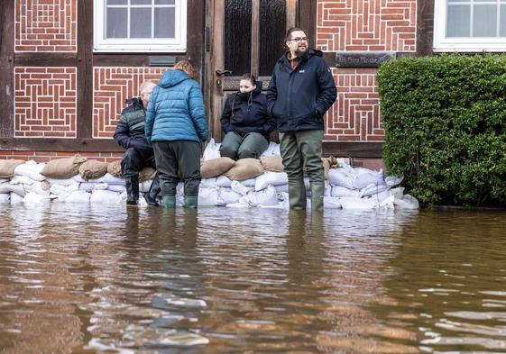 Los residentes se reúnen frente a una casa protegida por sacos de arena en una calle inundada en Verden