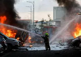 Un efectivo de emerencia apagando las llamas durante tras el ataque de Hamás