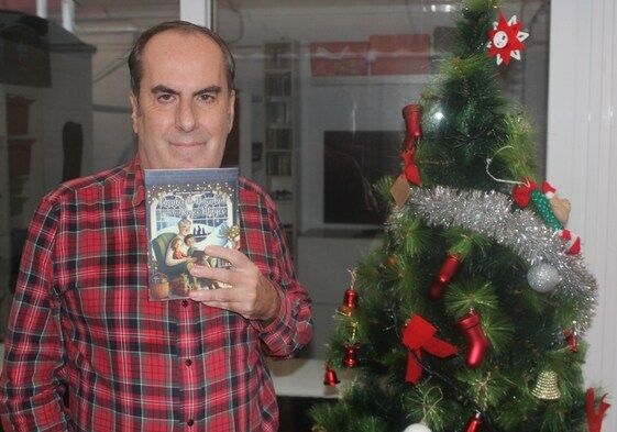 José Ramón Guzmán posa junto a un árbol de Navidad con su libro de cuentos.