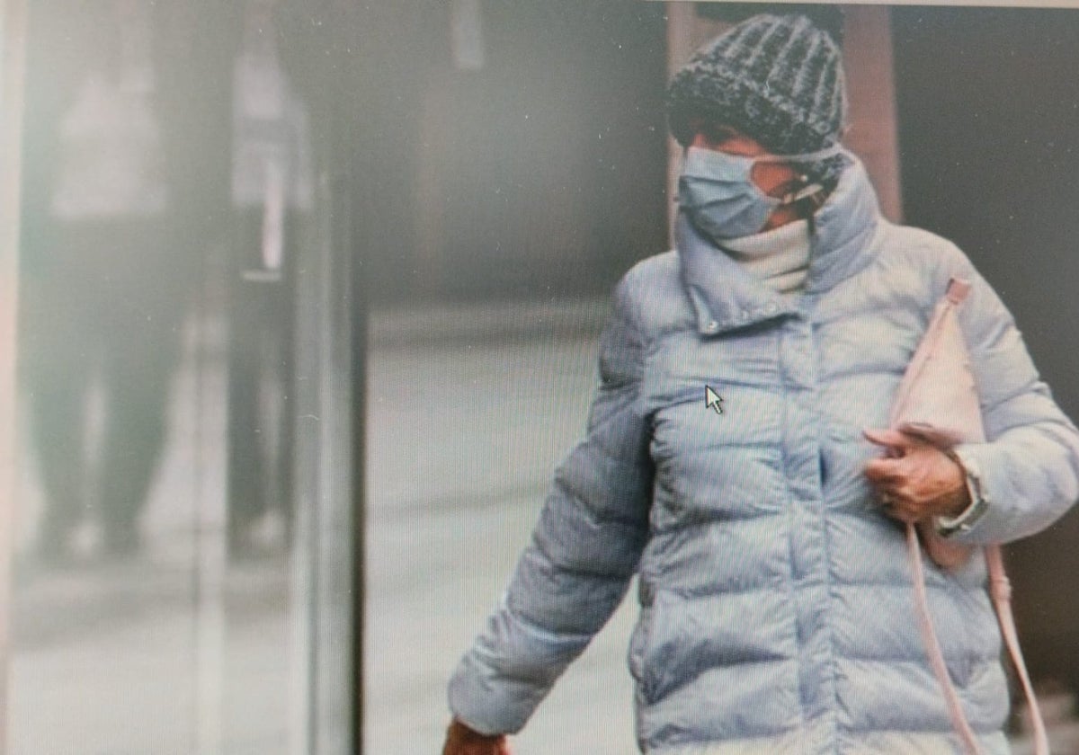 Una mujer camina con una mascarilla.