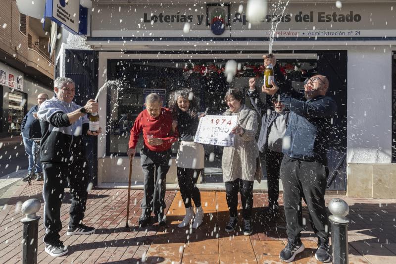 La propietaria de la administración número 24 de El Palmar (Murcia), Carmen María Alcaraz (3i), acompañada por su padre Salvador y su hermana Pilar (3d), celebran la venta de décimos del gordo del Niño.