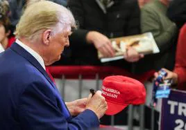 Donald Trump firma un autógrafo durante un mitín de campaña en Iowa