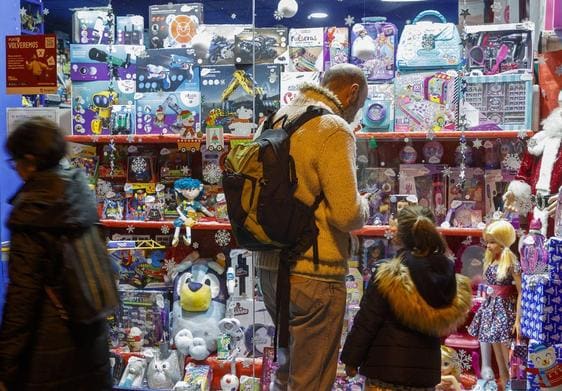 Un padre y su hija observan el escaparate de una juguetería.