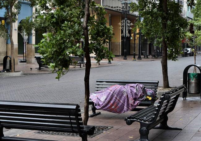 Una persona duerme en un banco en una calle de Guayaquil.