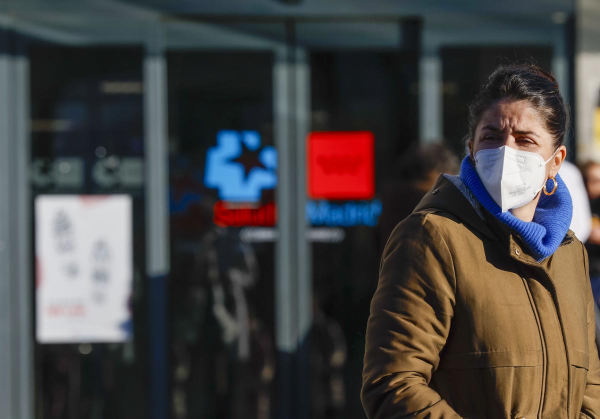 Imagen de una mujer con mascarilla en el exterior de un centro sanitario.