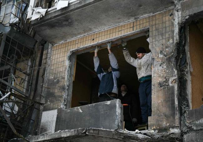 Vecinos de Donetsk examinan los daños en un edificio bombardeado por Rusia.