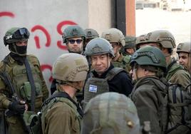 Netanyahu, protegido con casco y chaleco antibalas, habla con varios soldados durante una visita al frente del norte de Gaza.