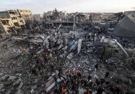 Decenas de palestinos buscan supervivientes entre los escombros de edificios derrumbados durante un bombardeo israelí en el sur de Gaza.