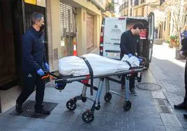 Dos trabajadores del retén fúnebre trasladan el cadáver de la víctima