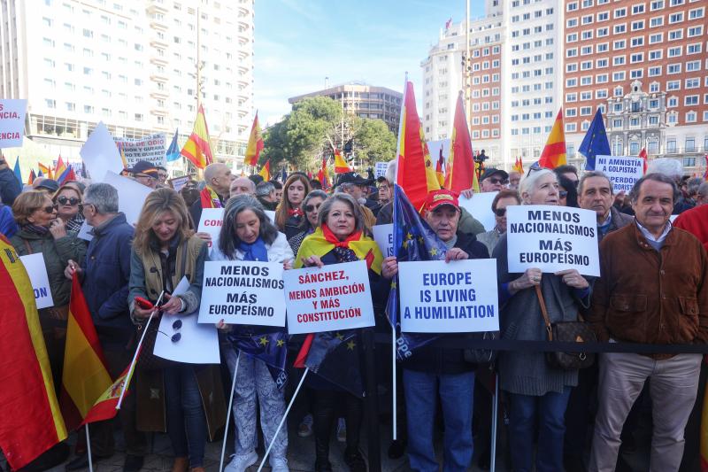 Varias personas sujetan carteles en la manifestación convocada por el PP en plaza España.