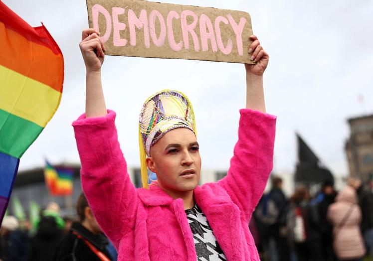 Un asistente a la protesta sostiene un cartel a favor de la democracia.