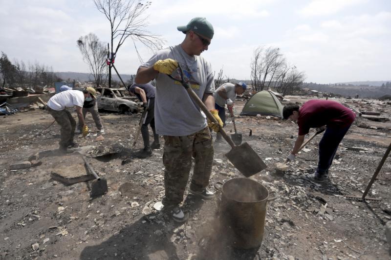 Habitantes del campamento irregular Pompeya recogen escombros tras los fuegos en Viña del Mar.