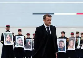 Emmanuel Macron pasa junto a los retratos de los 42 franceses asesinados en los ataques de Hamás durante un homenaje en París.