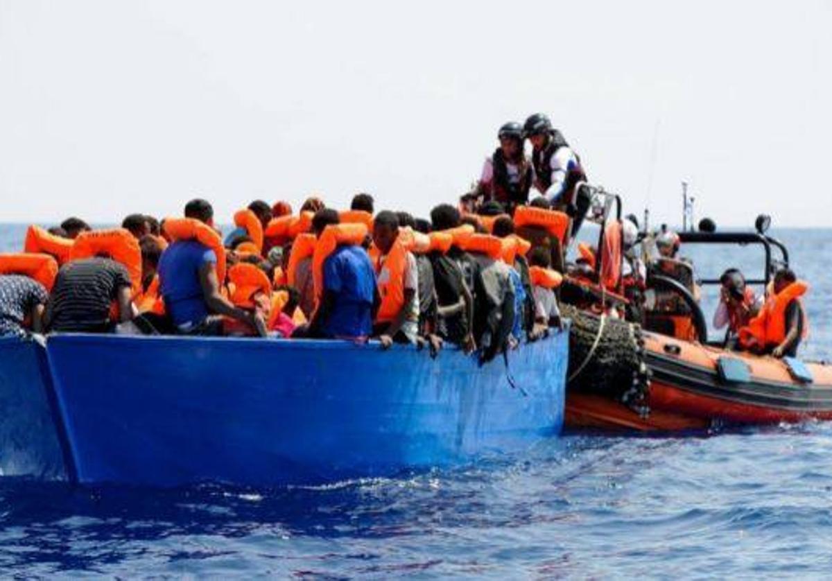 Varios inmigrantes rescatados en el mar antes de ser llevados a un barco de salvamento.