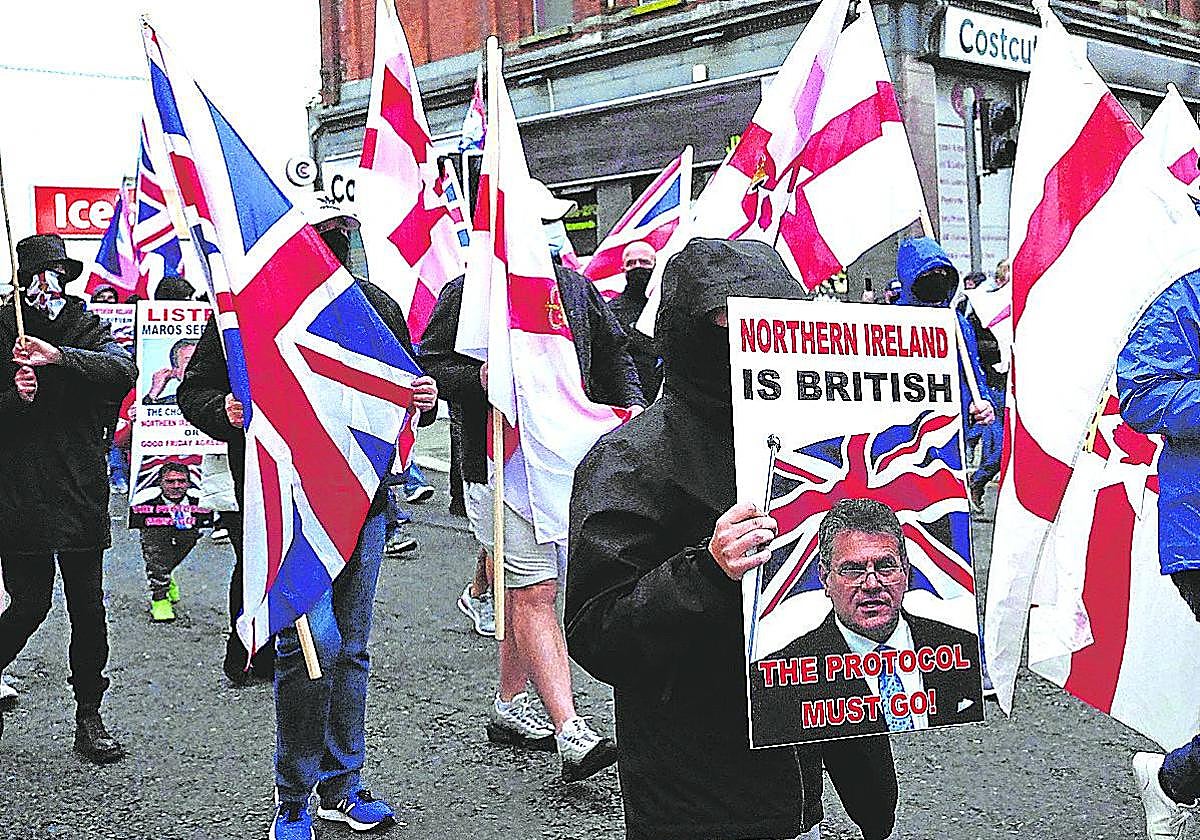 Manifestantes lealistas sostienen carteles y banderas durante una protesta.