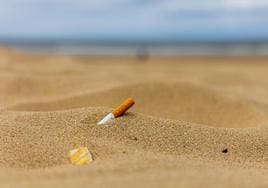 Colilla de tabaco abandonada sobre la arena de la playa.