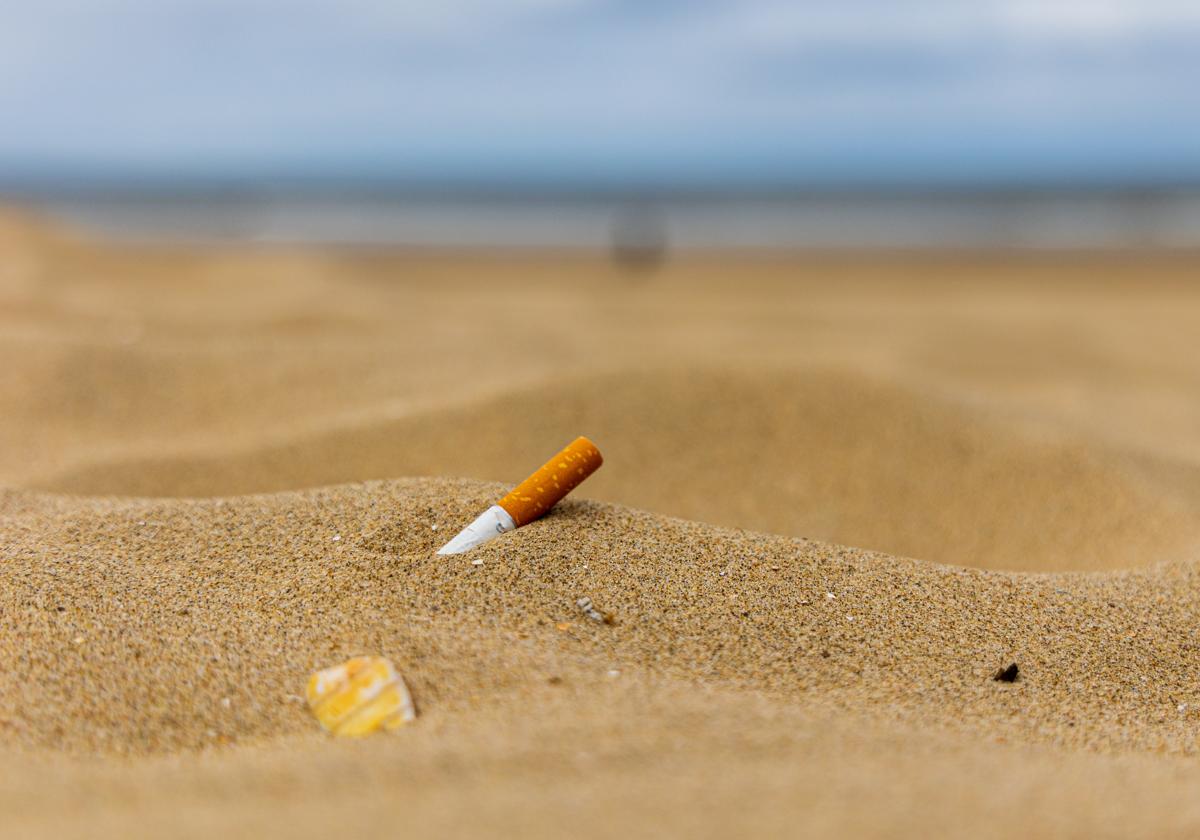 Colilla de tabaco abandonada sobre la arena de la playa.