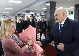 Lukashenko entrega un ramo de flores a una integrante de la comisión local de su colegio electoral en Minsk.