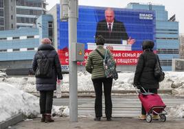 Dos mujeres moscovitas siguen el discurso de Putin a través de una pantalla instalada en una calle de Moscú.
