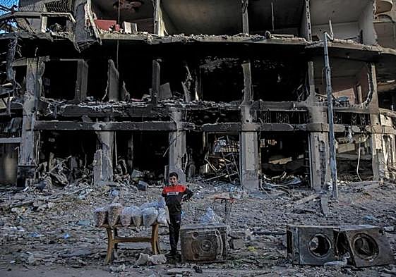 Un joven vendedor palestino espera a sus clientes junto a un edificio en ruinas en Gaza.