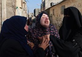 Una madre es consolada por varias vecinas tras perder a sus dos hijos gemelos en un bombardeo en Gaza.