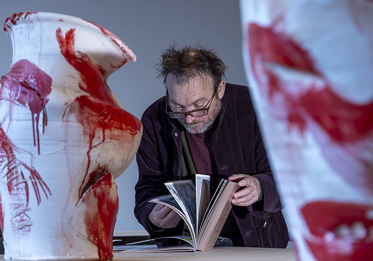 Barcelo consulta un catalógo entre dos de las vasijas policroamadas que exhibe en la Pedrera.