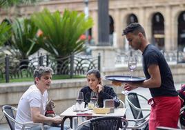 Un camarero sirve a unos clientes en una terraza de un bar de Bilbao.